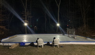 outdoor ice rink, nighttime, two people in chairs, hockey net