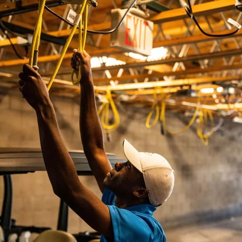 Electrician running wires overhead for LED fixture installation