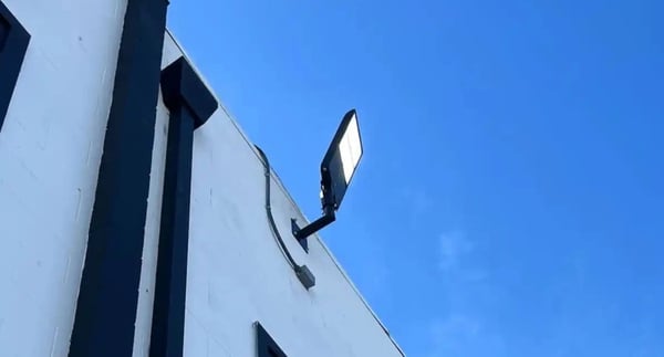 LED flood light installation with single arm bullhorn adapter on building wall