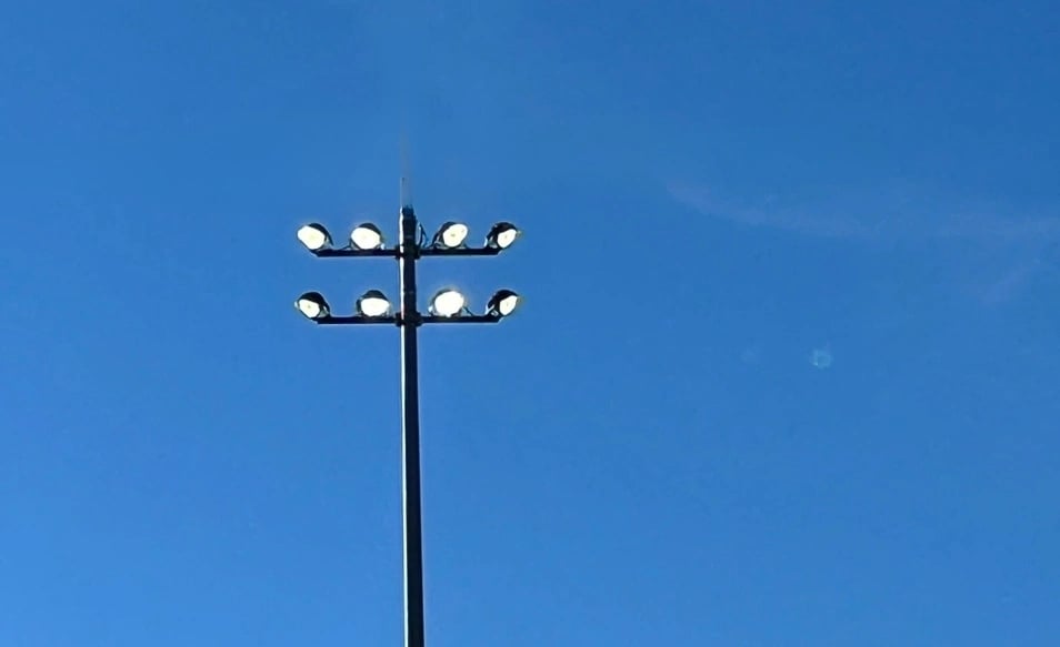 Round LED stadium fixtures installed on crossarm with trunnion mounts
